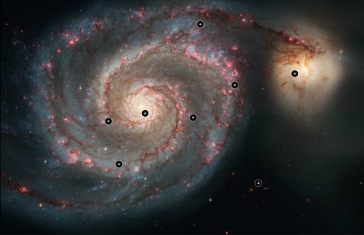 A visible wavelength view of the Whirlpool Galaxy, which shows a spiral galaxy filled with a bright yellow core of gas and dust and brown dusty arms with pink and blue stars within, and a smaller yellow galaxy to the top right.