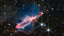 An infrared wavelength view of Herbig-Haro 46/47, which shows two orange lobes, one pointing to the bottom left and the other pointing to the top right with a bright orange star in between the two.