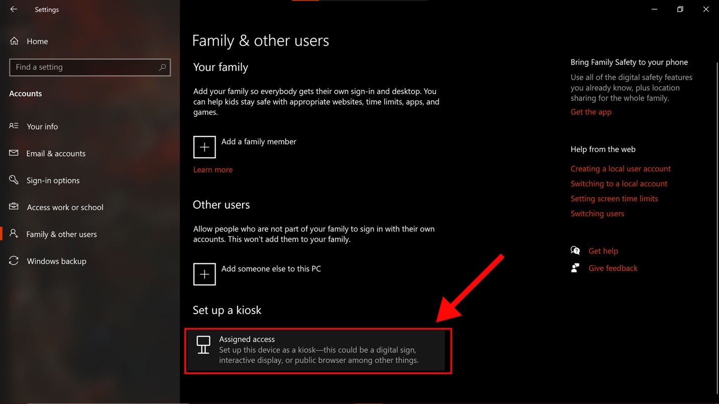 Screenshot of the “Family and other users” window as seen on a Windows computer. Toward the bottom, underneath the “Set up a kiosk” section, a large red arrow points to the "Assigned access" option, which is highlighted by a red rectangle.
