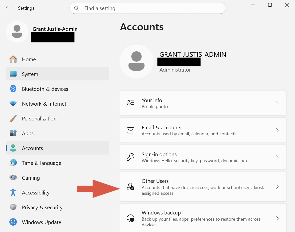 Windows 11 Settings window showing the “Accounts” section selected. The main area displays account information for an administrator. An arrow points to the “Other Users” option, indicating where to click next.