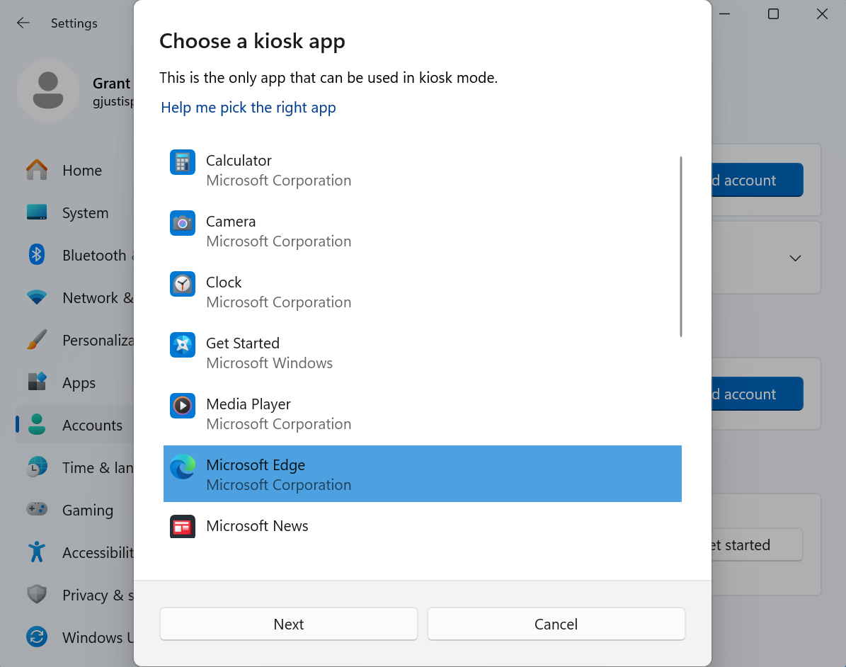 Dialog box titled “Choose a kiosk app” within the Windows Settings interface. The user is selecting an app for kiosk mode, and “Microsoft Edge” by Microsoft Corporation is highlighted. Other listed apps include Calculator, Camera, Clock, Get Started, Media Player, and Microsoft News. Buttons at the bottom include “Next” and “Cancel.”